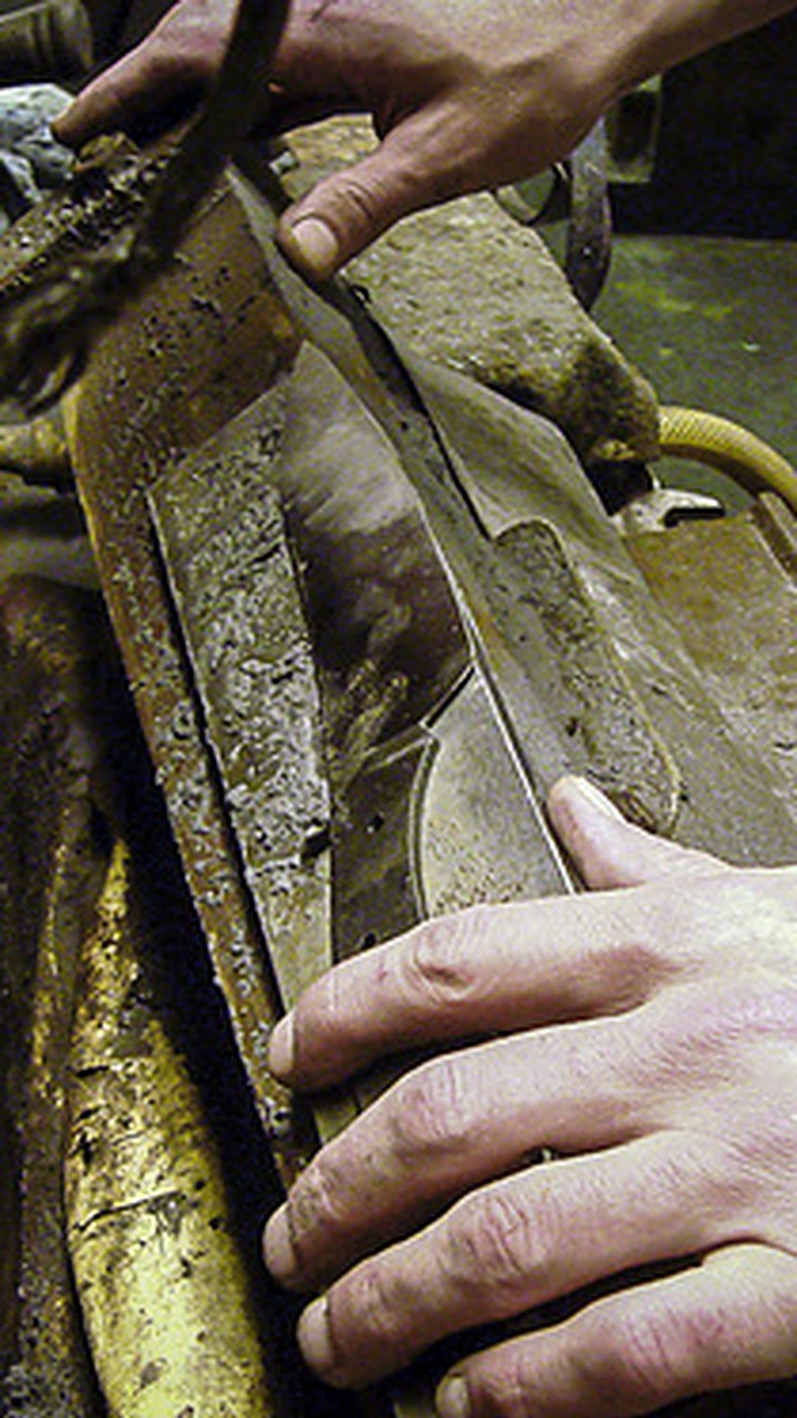 Hands guiding a knife blade on a grinding wheel in a Solingen workshop