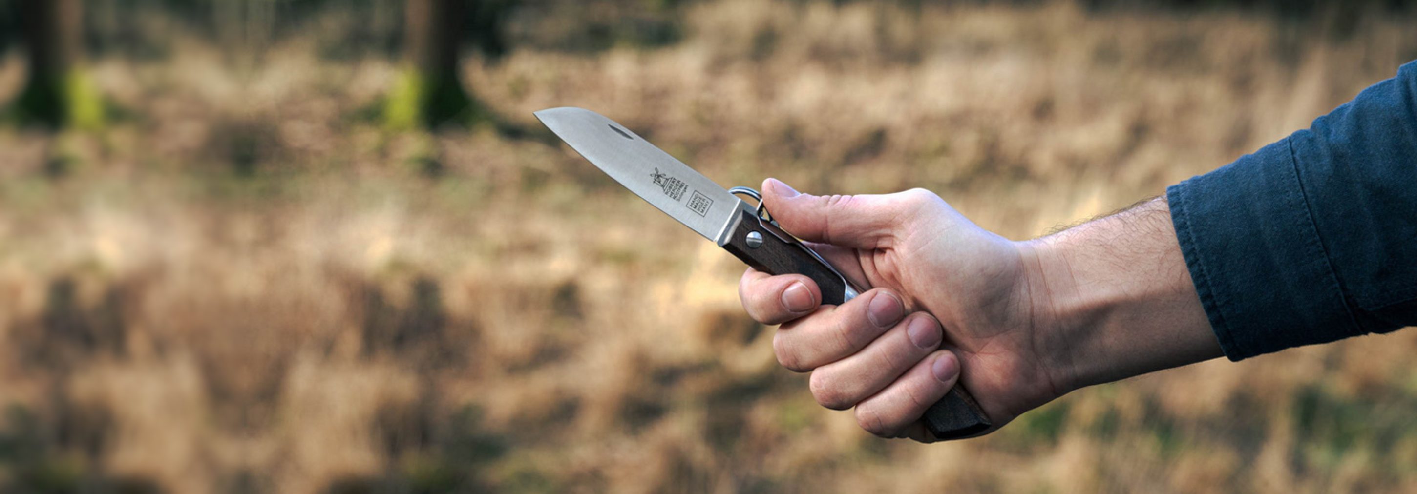 A hand holding an open Windmühlenmesser knife